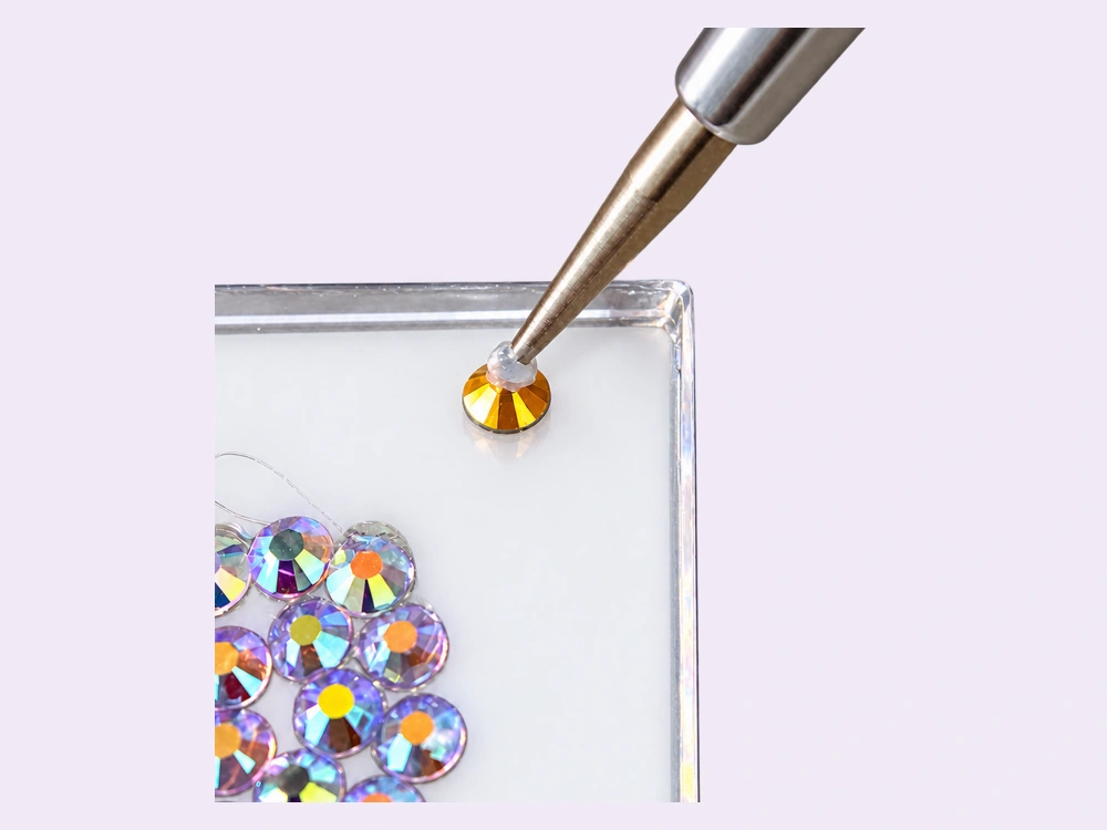 Gold rhinestone being placed onto the acrylic board